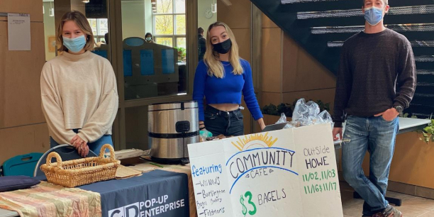 students standing in front of a table selling bagels