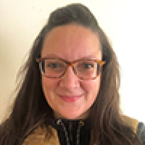 tracey is smiling at the camera and wearing glasses