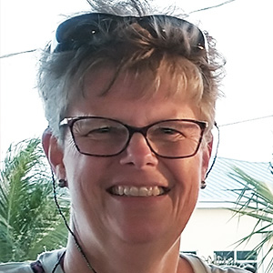 martha is smiling at the camera, she has short hair and is wearing glasses