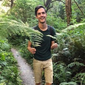 Bertrand Black on a wooded trail, holding ferns