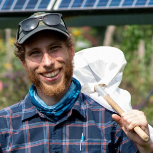 Jason holding a bug net in front of solar panels