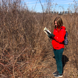 Michelle consulting a field guide in a woody thicket