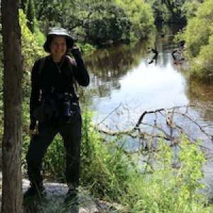 Sarah Morris outside in a wooded area near still water