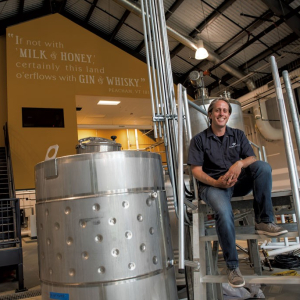 man standing next to distillery tank