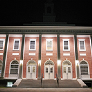 The front of Southwick Hall lit up at night showing the staircase to the entrance and the many windows of the brick building