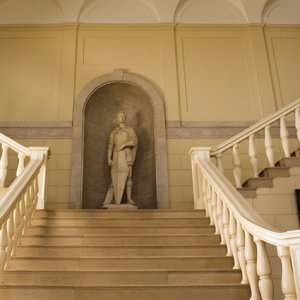 Grand staircase in the Fleming Museum. A white stone with a statue at the top of the landing.