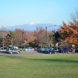 cars parked in a parking lot with autumn foliage and mountains in the background