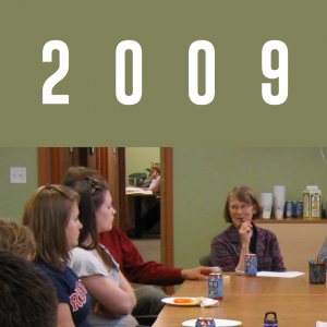 2009: Sue Dinitz sits at the head of the WID conference room table with a group of mentors.