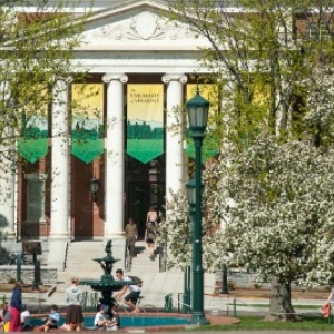 White trees in bloom in front of red brick and white column building.