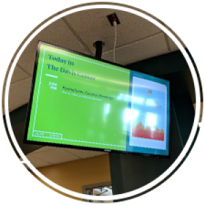 a flatscreen showcasing posters and events on the wall