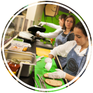 three students preparing grilled cheese sandwiches at a kiosk for feel good
