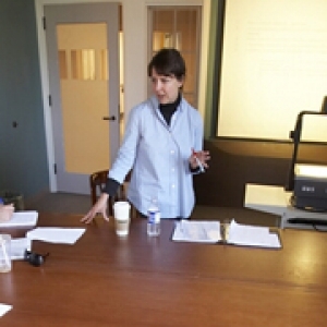 Foundational Writing and Information Literacy Instructor describing a writing assignment to three students at a group table