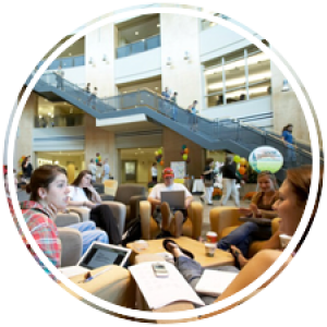 numerous students lounging and discussing on the ground floor of the atrium