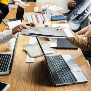 Group of people sitting around table, opening laptops.