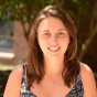 Amy Wheeler-Sutton: Amy is female, has medium length brown hair, brown eyes, white skin, and is in her thirties. She has a starfish necklace and blue patterned dress on. The photo is taken outdoors in the sun.