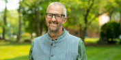 Portrait of Mark, smiling on a sunny day on the UVM green