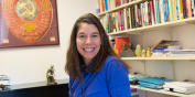 Michelle Commercio in her office with a map on the wall and bookshelves lined with books