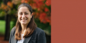 Danielle, smiling outdoors with hints of fall color in the trees behind