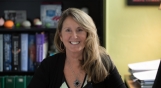 Karen seated at her desk in her office with booklined shelves in the background