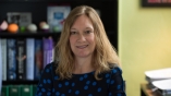 portrait of Kelly in an office with book lined shelves