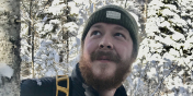image description: man with beard and hat among snowy trees