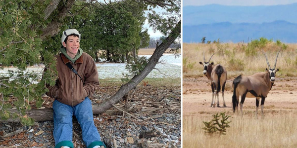 Ben Simmons smiles while he sits on a log on a stoney beach and African oryx graze in New Mexico.