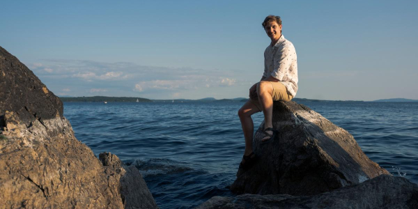 Andrew McCracken sits on the edge of Lake Champlain 