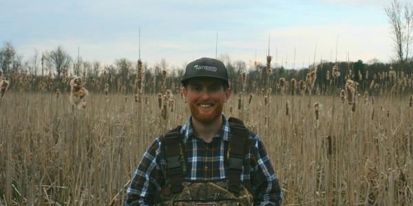 Sam Buswell standing in among reeds in a wetland in Vermont