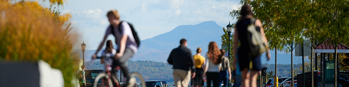Student walk and bike across campus, a mountain is in view.