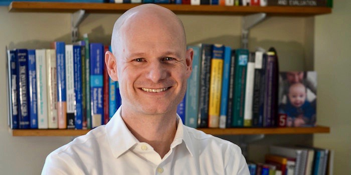 photo of Jesse Suter smiling in front of book shelf