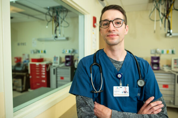 Matt Saunders, UVM ’20, facing the camera wearing a blue shirt in a medical setting